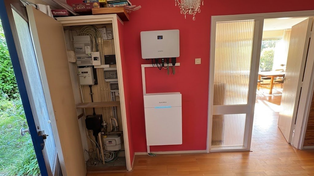 Sungrow omvormer en thuisbatterij op rode muur met meterkast